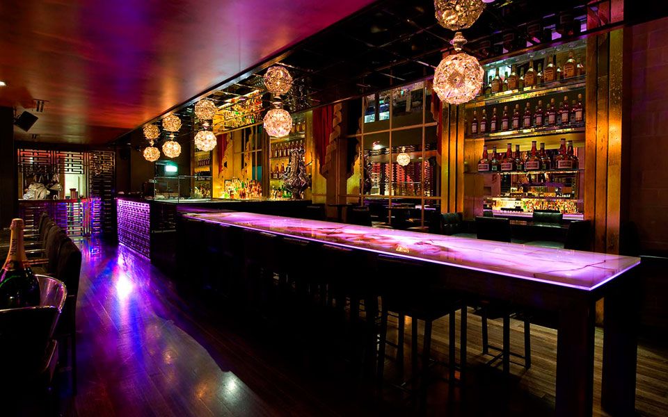 Luxurious cocktail lounge with dim lighting, elegant seating, and a bartender serving signature drinks.